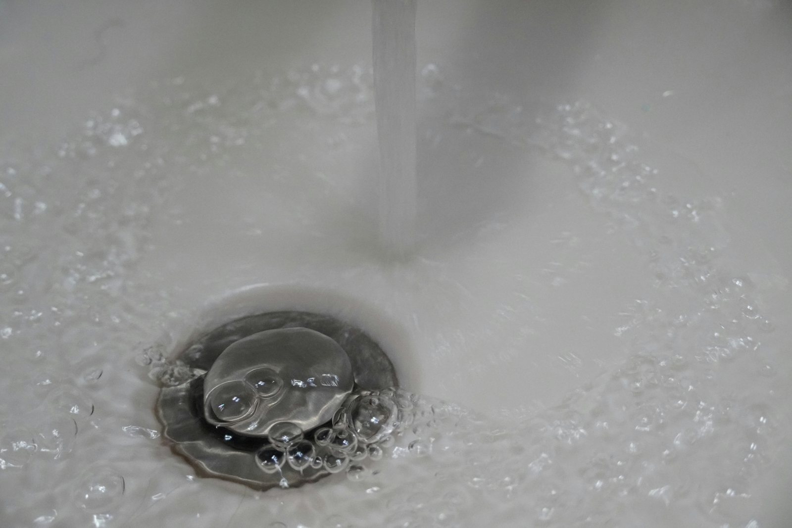 Water flowing into a residential bathroom basin and drain